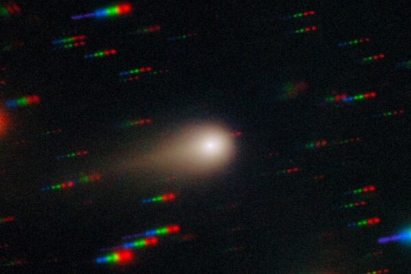an image of a comet streaking through space with the stars around it reflecting rainbows