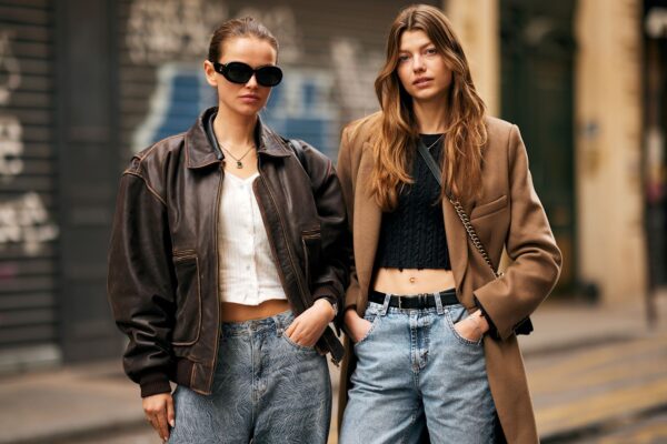 two fashion week attendees wear brown coats and jackets with denim