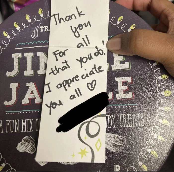 A thank you note atop a tin of snacks reads: "Thank you for all that you do! I appreciate you all" with a heart symbol