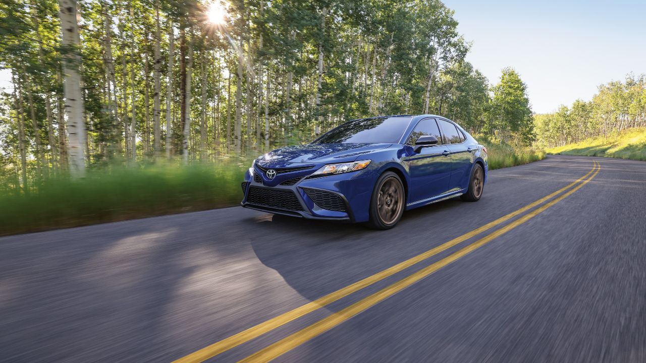 A blue 2024 Toyota Camry in the forest day.
