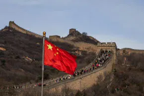 A Chinese flag flies with tourists hiking along the Great Wall, near Beijing, China, November 10, 2025; illustrative. (photo credit: Cheng Xin/Getty Images)