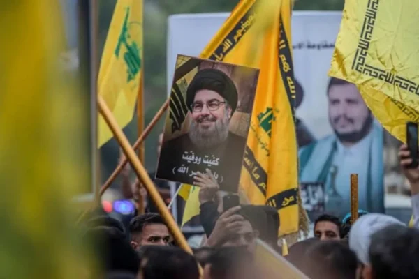 Supporters of an Iraqi armed faction hold flags of Lebanon's Hezbollah and a portrait of assassinated Hezbollah leader Hassan Nasrallah (C) during a protest in Baghdad on December 5, 2025. (credit: Murtadha RIDHA / AFP via Getty Images)
