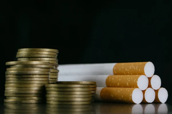 Six cigarettes beside stacked-up coins.