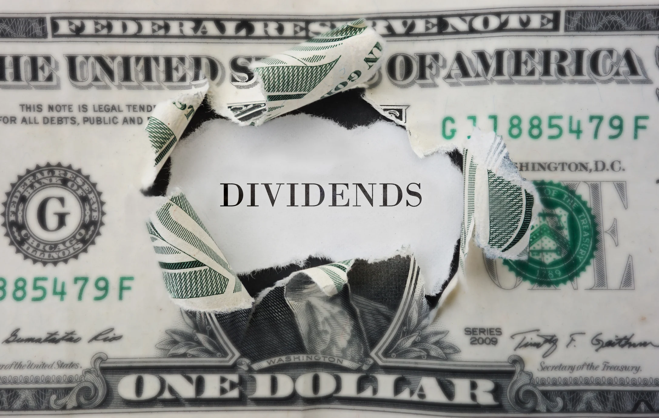 A torn dollar bill revealing the word dividends.
