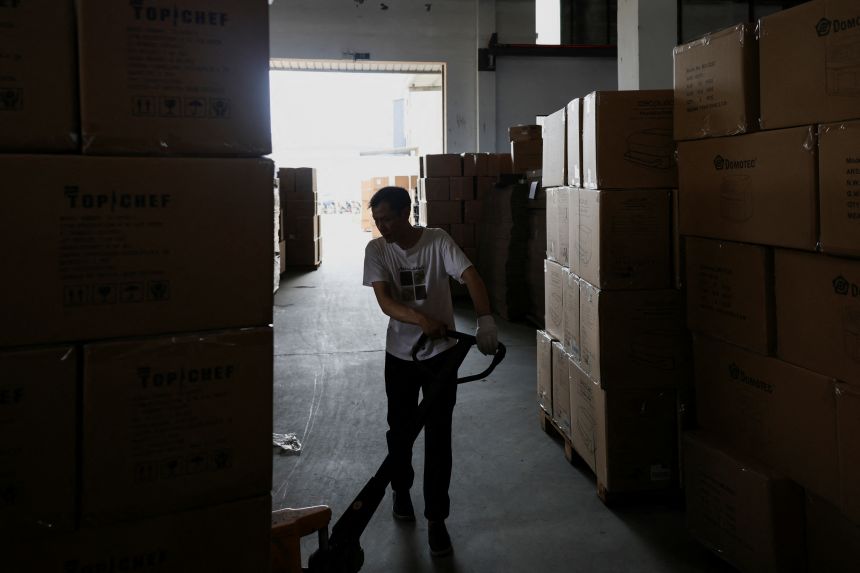 An employee of Gstar Electronic Appliance Co., Ltd moves finished products on a pulling cart in the factory in Ningbo, China, on May 19, 2025.