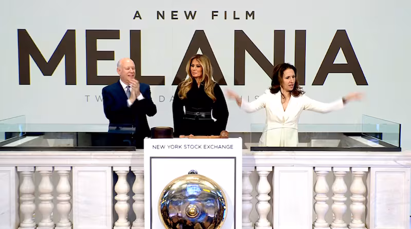 A woman gestures to the right of Melania Trump