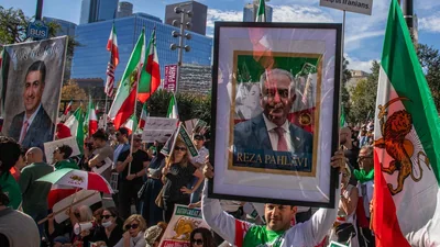 An unidentified man holds a picture of Reza Pahlavi while members of the Iranian community and supporters hold signs and pre-regime Iranian flags during a "Solidarity with the People of Iran" event in front of City Hall in Downtown (Getty Images via AFP)