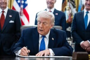 Donald Trump, center, signs an executive order in the Oval Office of the White House (Bloomberg)