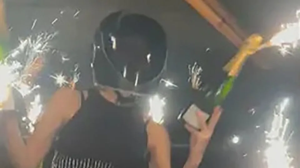 An image shared on social media shows what appears to be a waiter holding champagne bottles with sparklers attached to them. A portion of this image was blurred by CNN to protect identities. - From social media