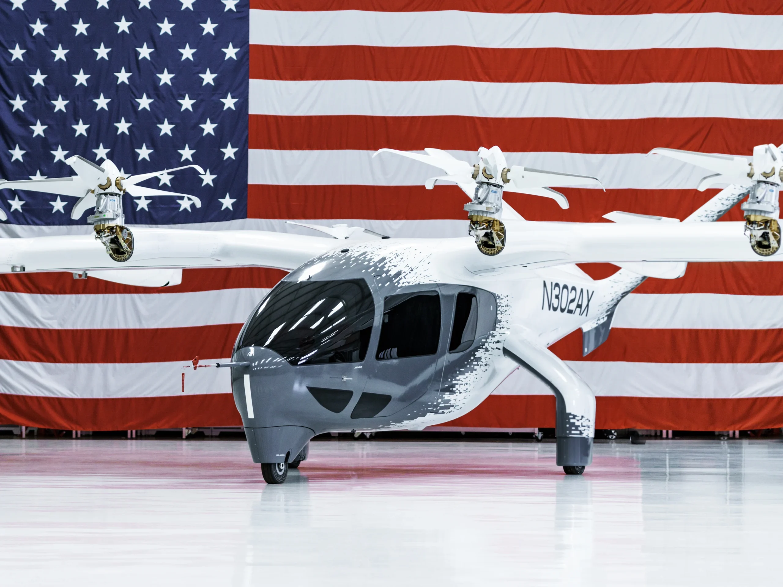 An Archer Aviation Midnight aircraft in front of an American flag.