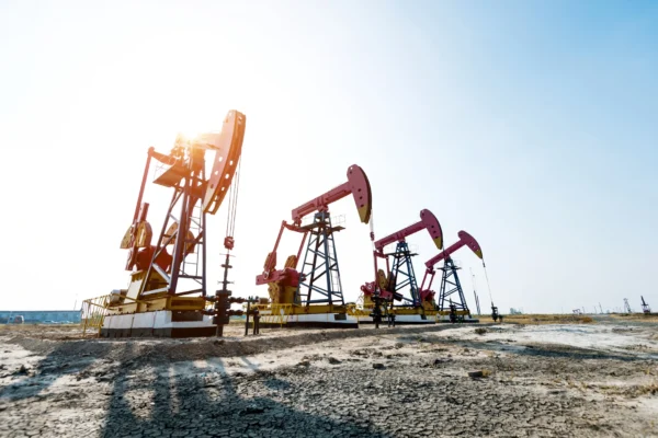 four oil well extraction rigs sit on a platform with the sun shining behind them