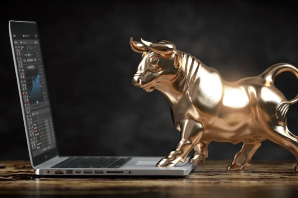 A sculpture of a golden bull standing on a laptop computer.