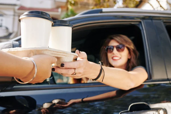 Person buying prepared coffee at a drive-thru.