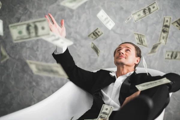 A seated person looking at money flying in the air.