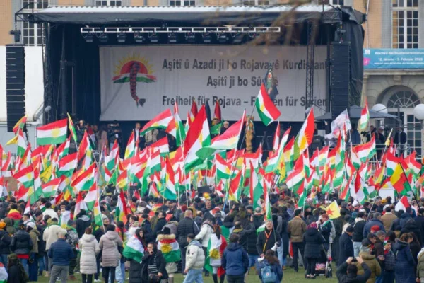 Participants hold flags and placards at a large rally in solidarity with the Kurdish people in Syria. Henning Kaiser/dpa