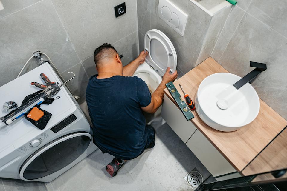 A professional plumber installing a toilet in a home