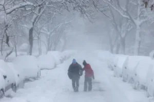 Two people walk in a snowy scene.