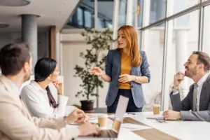 Female manager standing at meeting room and having briefing with her team.