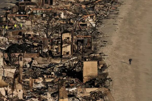 FILE - A person walks on the beach next to homes damaged by the Palisades Fire, Jan. 16, 2025, in Malibu, Calif. (AP Photo/Jae C. Hong, File)
