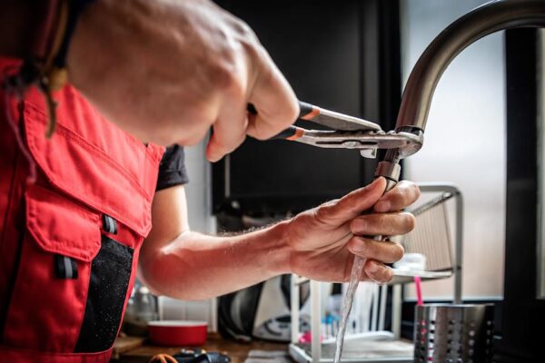 A plumber repairing a kitchen faucet