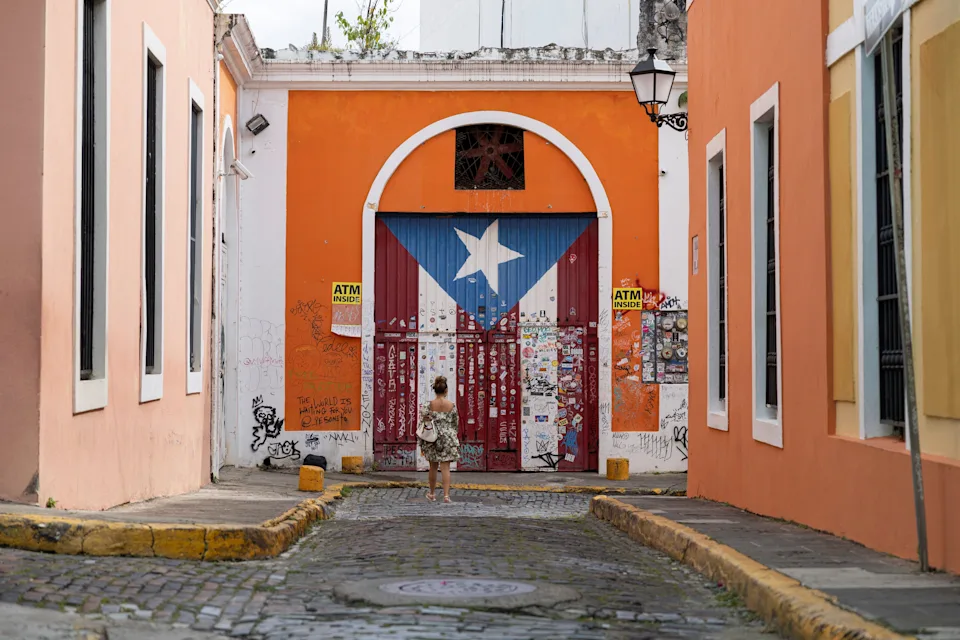 A woman takes photos of a gate with the Puerto Rican flag painted on it, in Old San Juan, Puerto Rico, Oct. 28, 2024.