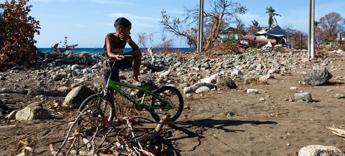 A young boy sits on a green bicycle amidst rubble and debris in Guamá, Santiago de Cuba, after Hurricane Melissa caused widespread destruction. No lives were lost in the evacuation.