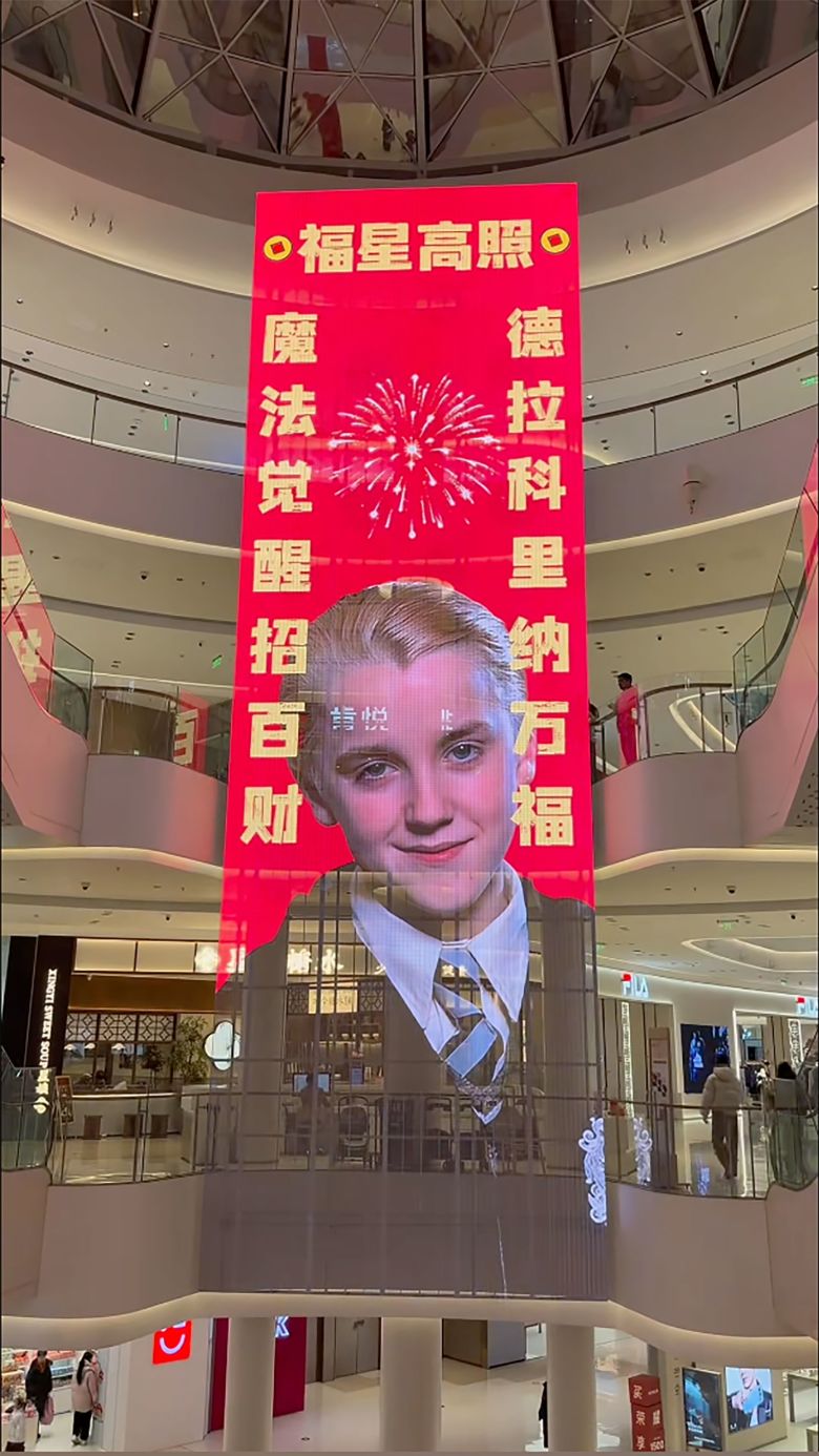 A shopping mall in central Henan province hangs an electronic banner showing a Chinese spring festival couplets featuring Malfoy at the center.