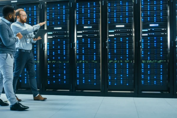 Two people walk through a server rack inside a data center.