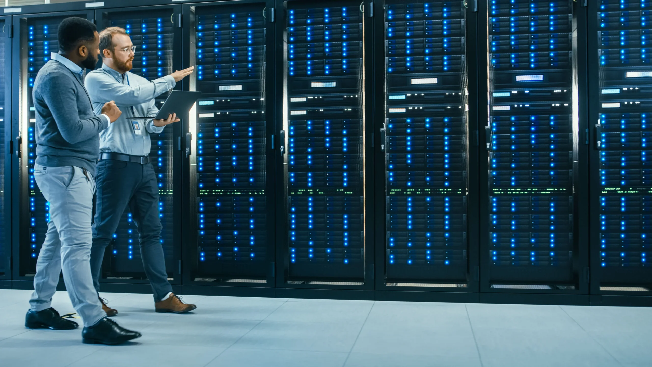 Two people walk through a server rack inside a data center.