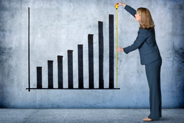 A person measuring a chart showing growth.