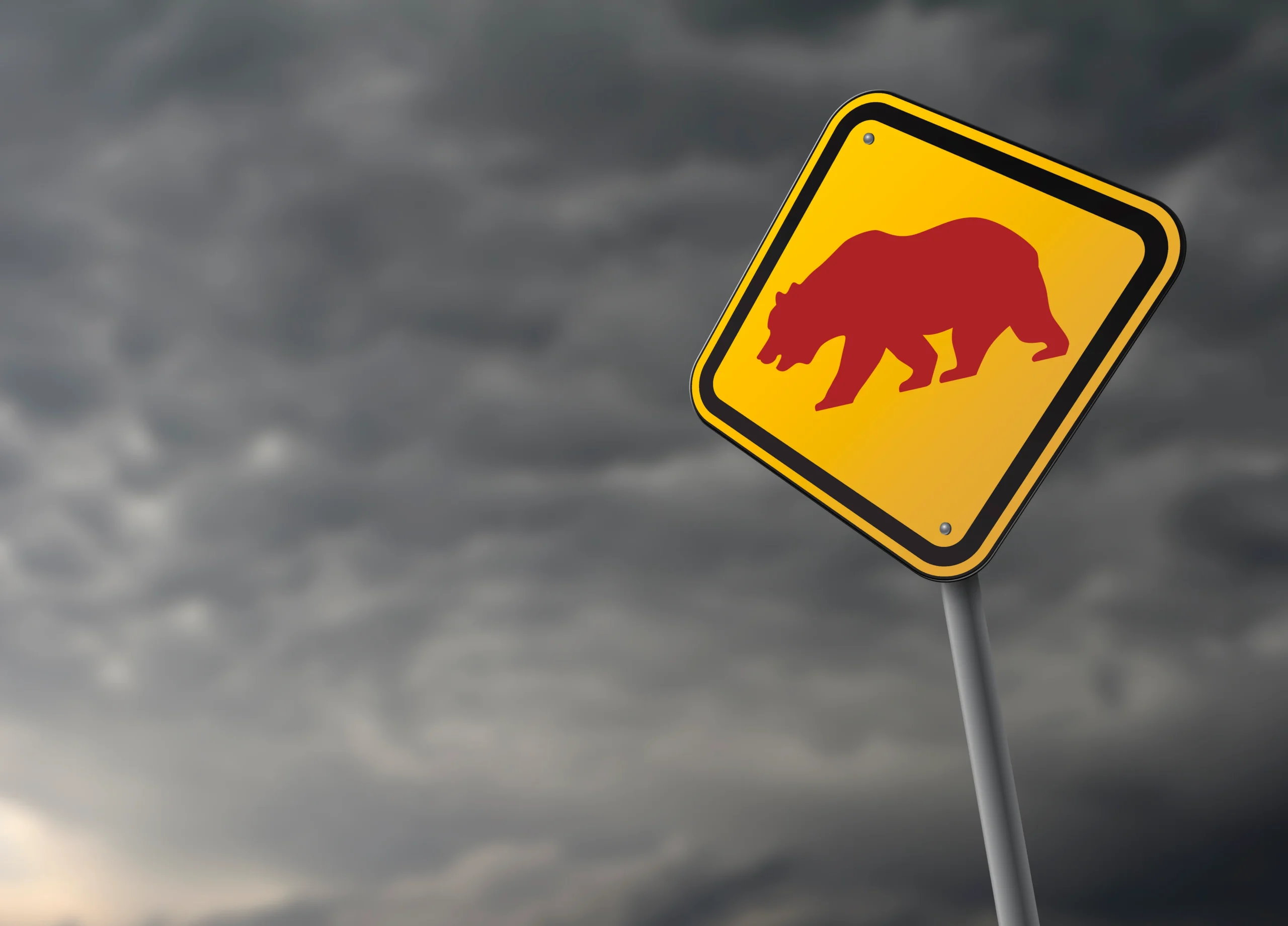 A sign with a bear on it set against a stormy sky.