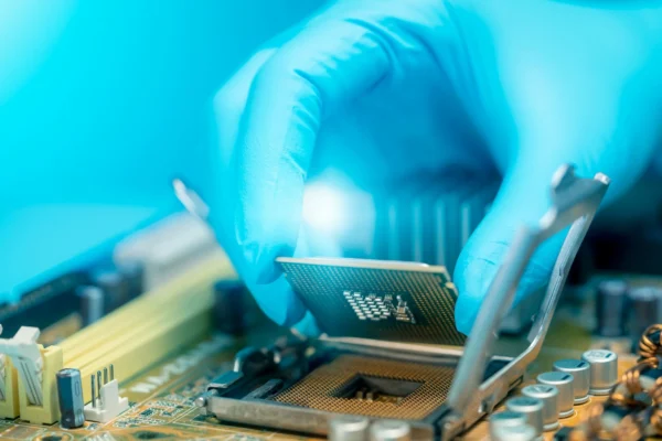 Gloved hand holding semiconductor chip.