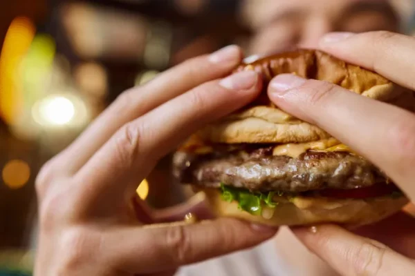 Two hands hold up a cheeseburger