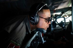 A man in uniform inside a plane, wearing sunglasses and headphones.