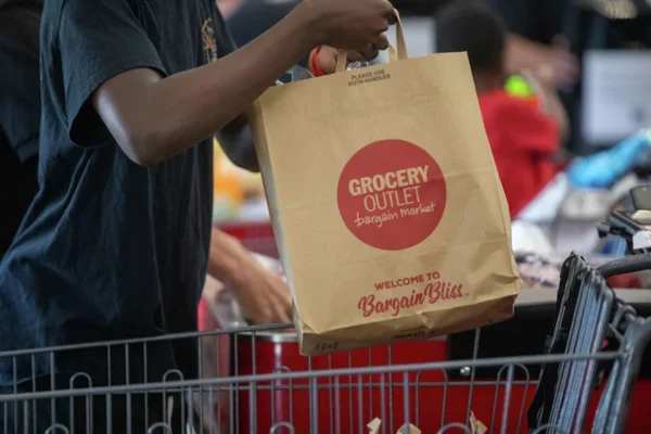 A customer places a bag of food items into a shopping cart at Grocery Outlet in Oakland, Calif., on June 7, 2024. (Douglas Zimmerman/SFGATE)