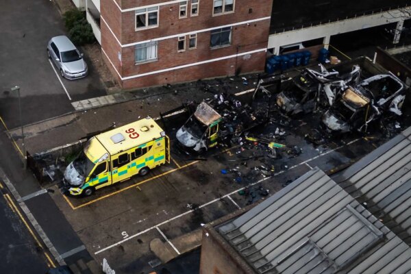 An aerial photograph showing three blackened and burned out ambulances and one badly damaged one, parked outside a building.