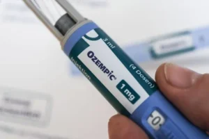 A hand holds an Ozempic injection pen, labeled with "1 mg" and "3 ml" dosage information, used for diabetes management