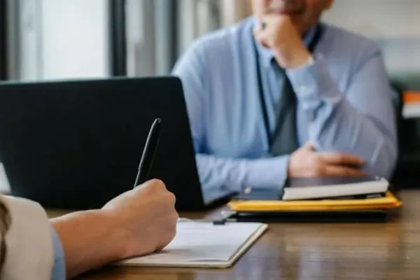 A job candidate writes on a document while meeting with an interviewer across a desk. Photo: Sora Shimazaki / Pexels