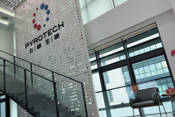 A two-story interior with many windows features a mural with the word “Pyrotech” and a logo of 10 circles arranged in a circle.