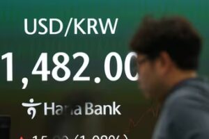 A dealer walks past near a screen showing the foreign exchange rate between U.S. dollar and South Korean won at a dealing room of Hana Bank in Seoul, South Korea. (AP)