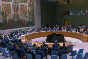 A diplomatic meeting at the United Nations Security Council with delegates seated around a large circular table.