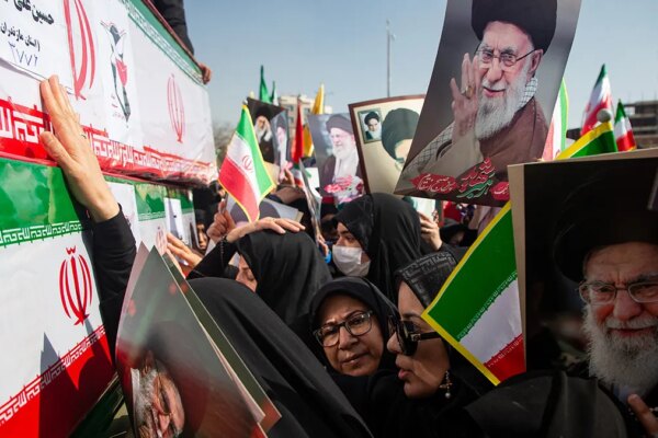 Mourners reaching out to touch coffins while holding pictures of Ayatollah Ali Khamenei during a funeral in Isfahan.