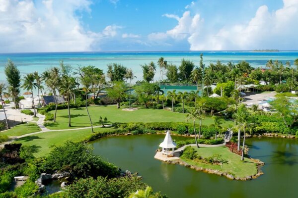 Pristine blue waters of the Micro Beach and the far-off Managaha Island backdrops a perfectly manicured garden with pond in Saipan, Northern Mariana Islands.