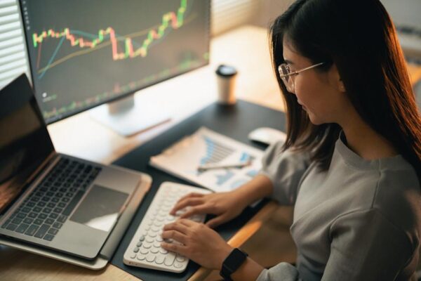 A person typing on a keyboard with a graph showing on the computer monitor.