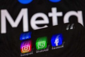 The Instagram, Facebook, and WhatsApp apps can be seen on a smartphone display in front of the logo of the internet company Meta. Jens Büttner/dpa