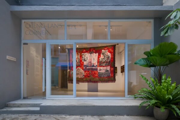 Exterior view of Cheng-Lan's Corner, Hong Kong, showing Cian Dayrit's tapestry A Country, A Body visible through the ground-floor gallery's glass facade.