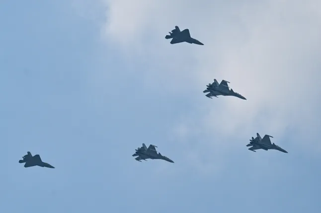 Shenyang J-15 (lead and middle aircraft) and Shenyang J-35 (back) jet fighters perform a flyby during a military parade marking the 80th anniversary of victory over Japan and the end of World War II, in Beijing's Tiananmen Square on September 3, 2025.