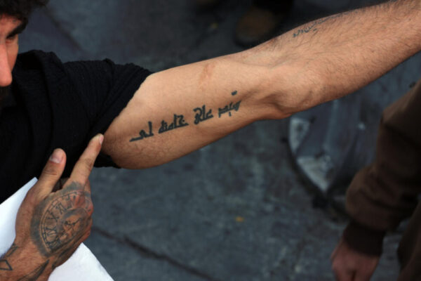 An Iranian man shows his tattoo with the name of the country's slain supreme leader Ayatollah Ali Khamenei during a rally to commemorate his death in Tehran