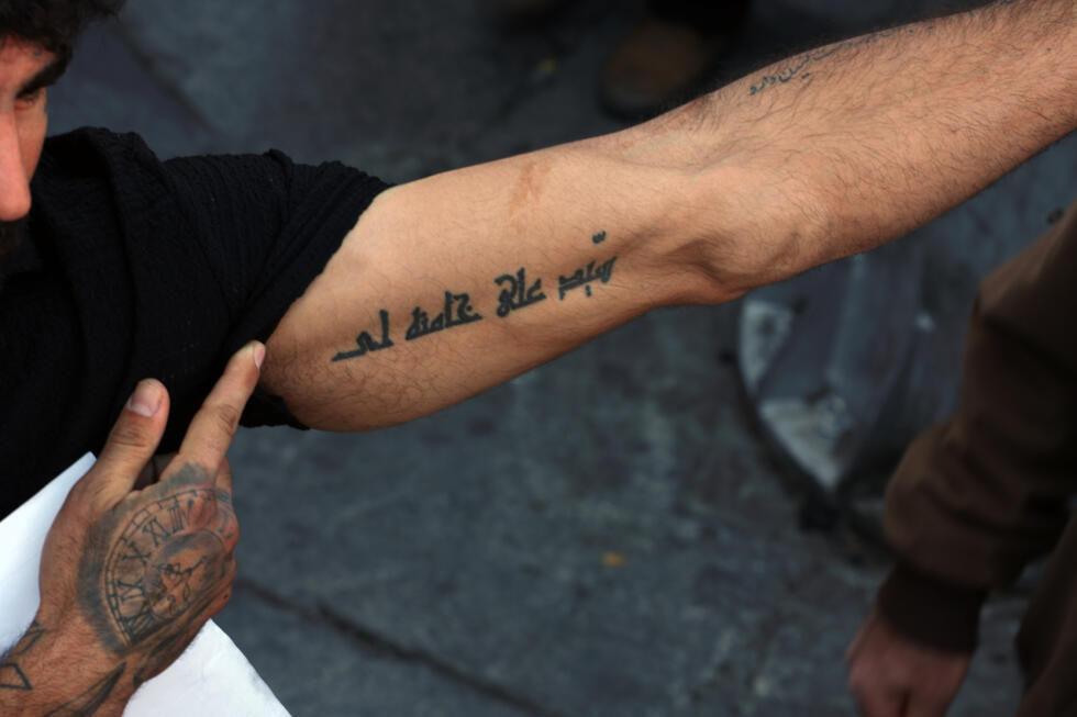 An Iranian man shows his tattoo with the name of the country's slain supreme leader Ayatollah Ali Khamenei during a rally to commemorate his death in Tehran
