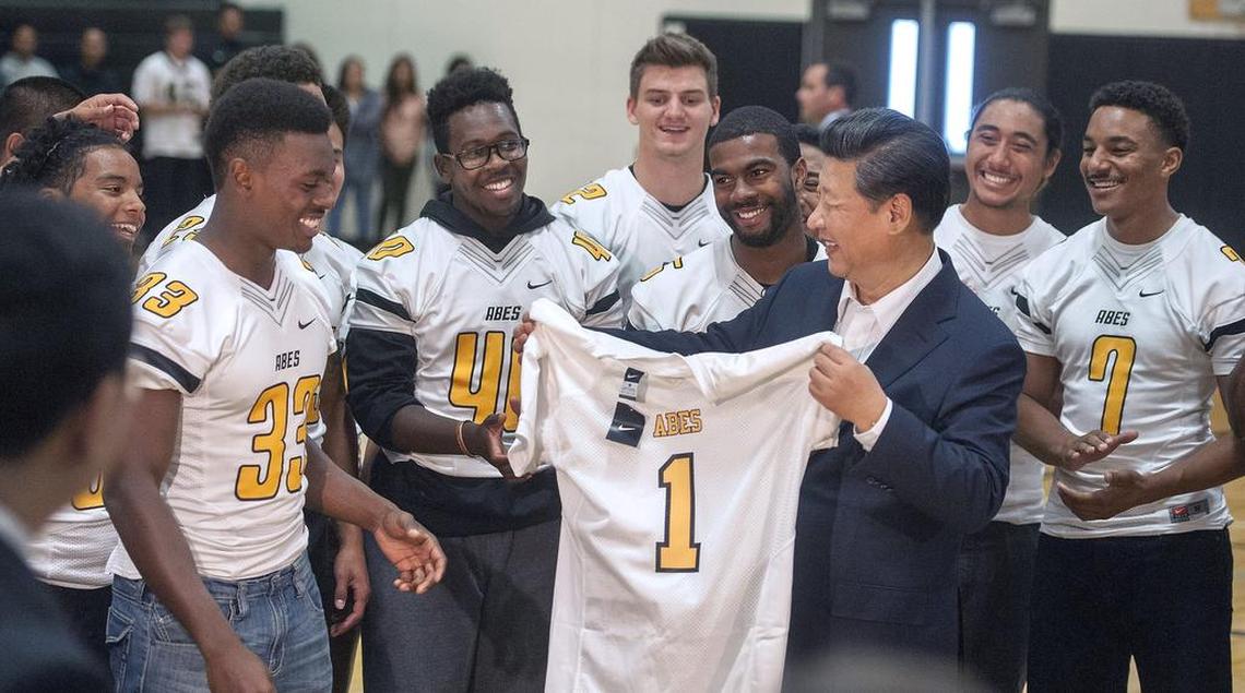 Members of the Lincoln football team laugh with Chinese president Xi Jinping after giving him a team jersey to commemorate his visit to Lincoln High on Wednesday, Sept. 23, 2015.